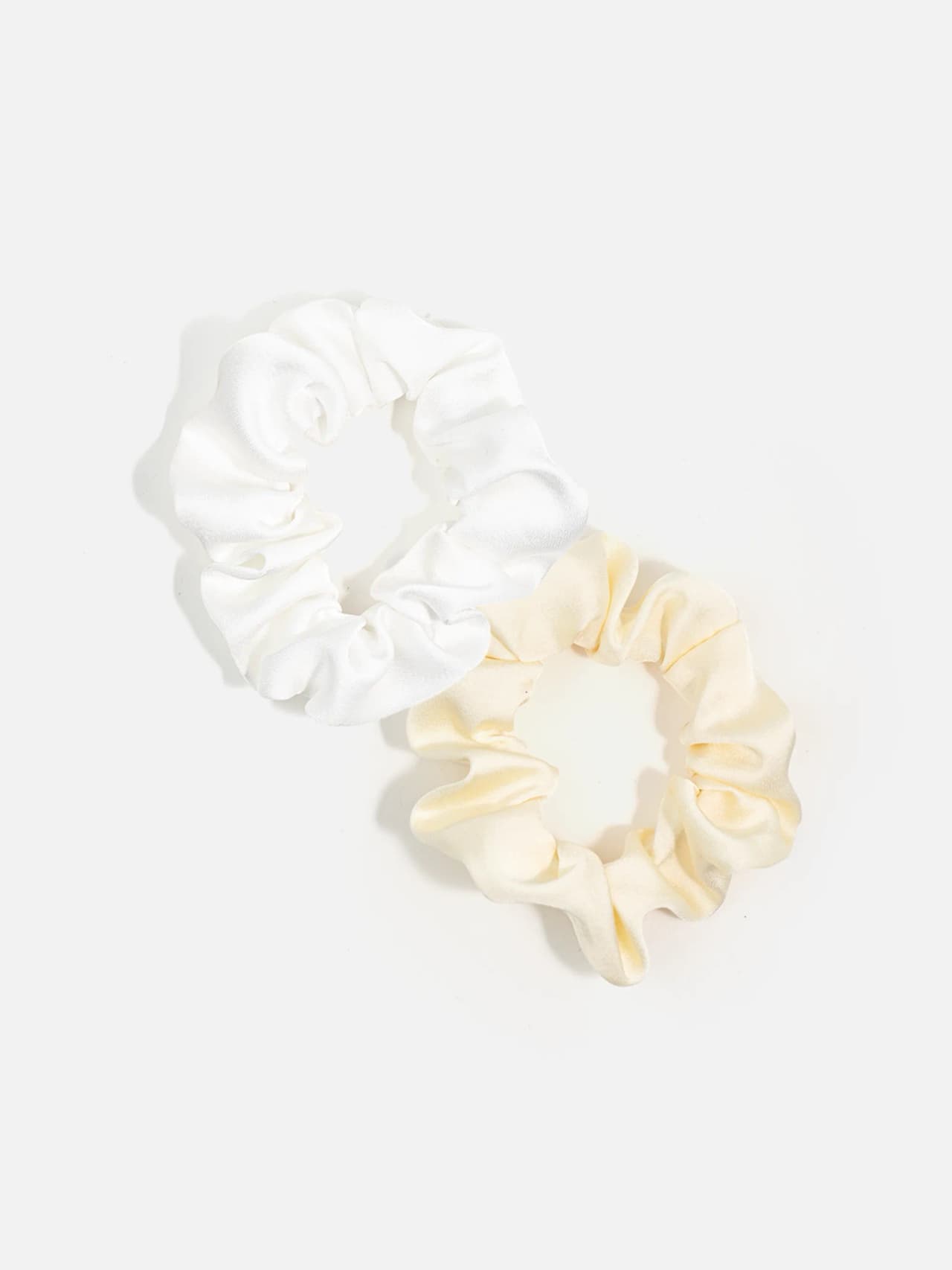 Två scrunchies i vitt och vanilj på ljus bakgrund