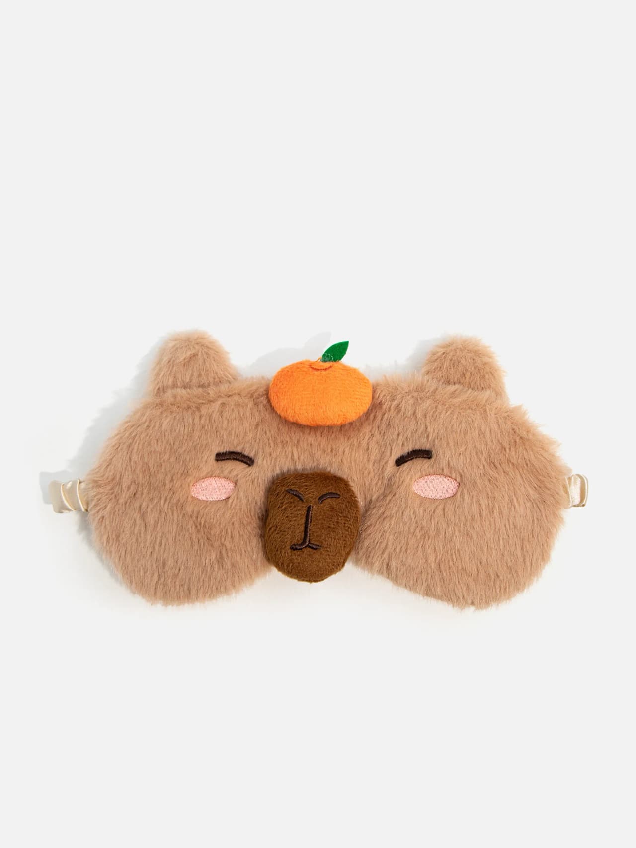 Fluffig brun kapibara sovmask för barn med rundade öron, broderat ansikte, rosa kinder och liten orange fruktdetalj på huvudet