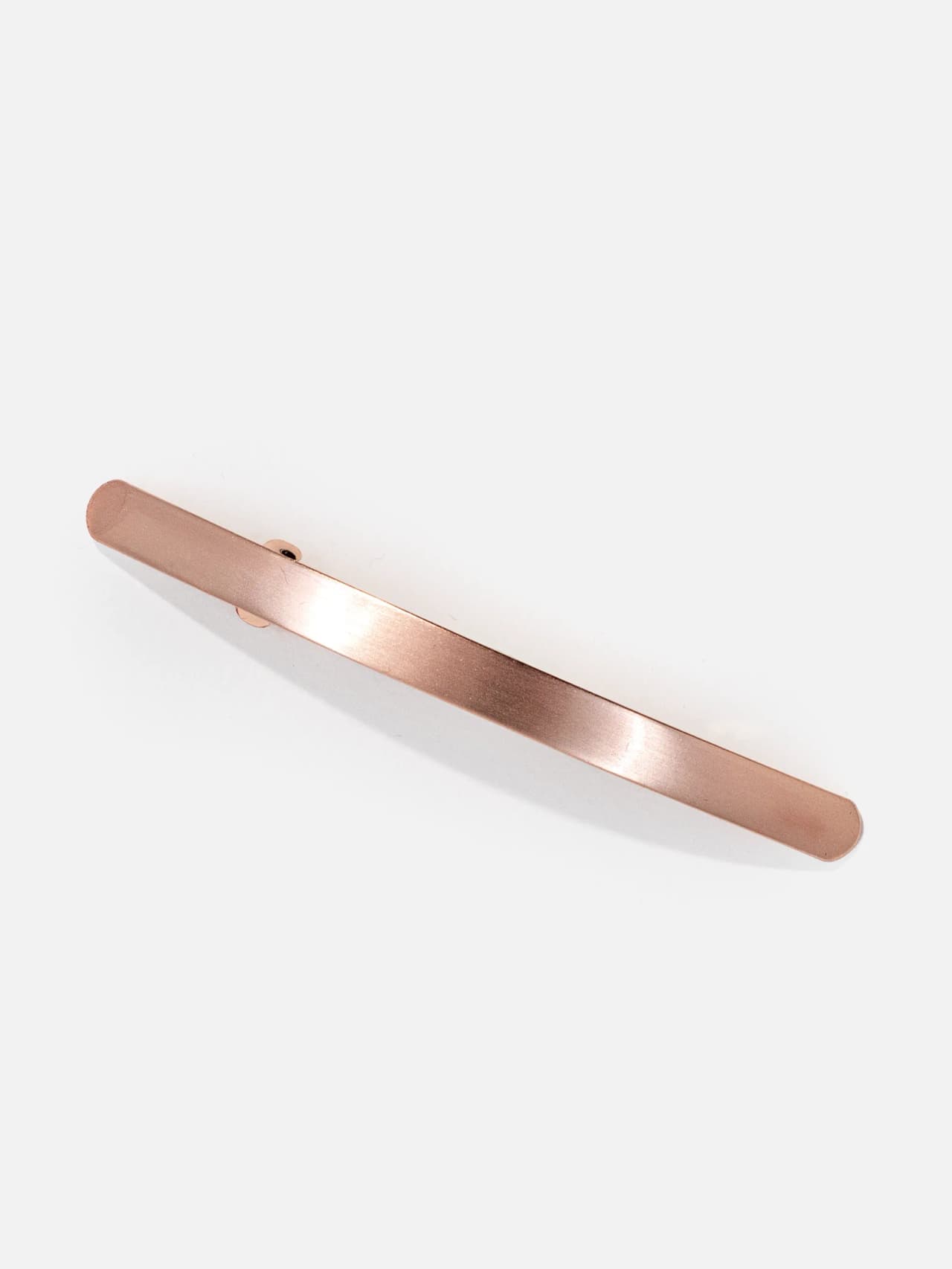 Slätt roséguldfärgat hårspänne i metall, 10 cm, på vit bakgrund.