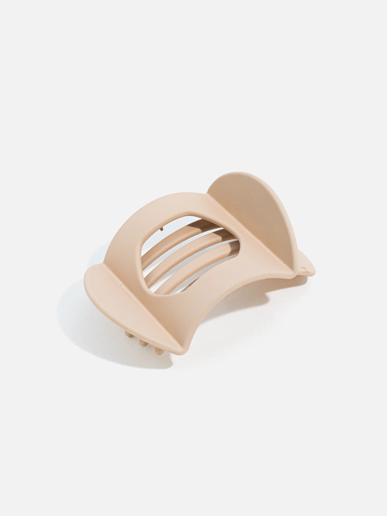 Närbild på oval hårklämma i beige ton med tydlig mittsektion och säkert grepp