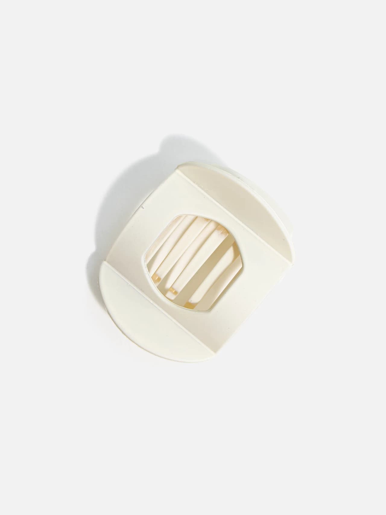 Oval hårklämma i krämvit ton med ribbad design, sedd uppifrån