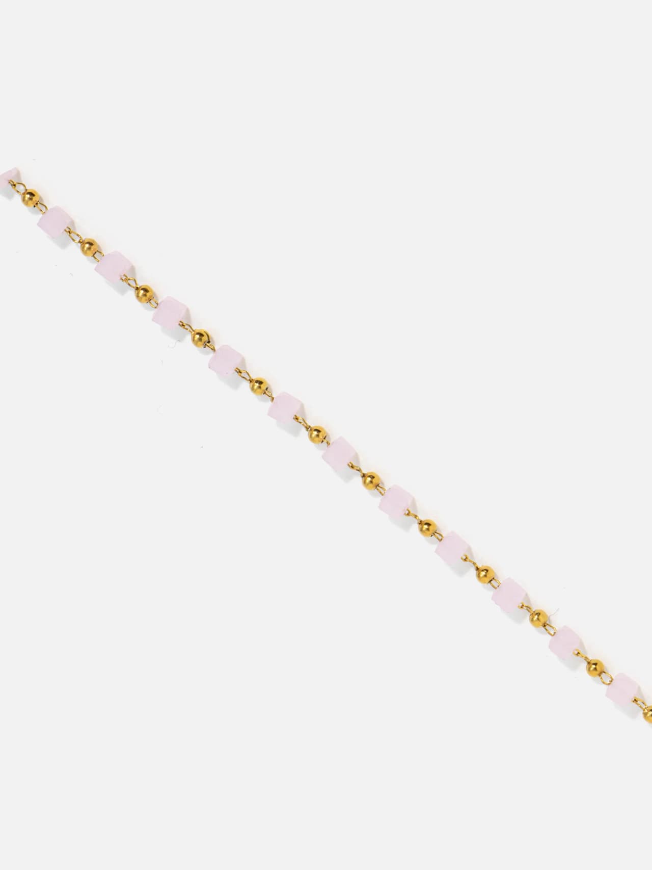 Närbild på rosa kristallkuber och polerade guldkulor på guldpläterad stålkedja