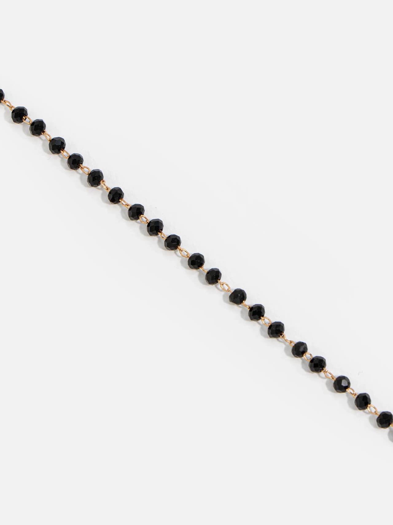 Närbild på facetterade svarta kristallpärlor på guldpläterad rosary-kedja
