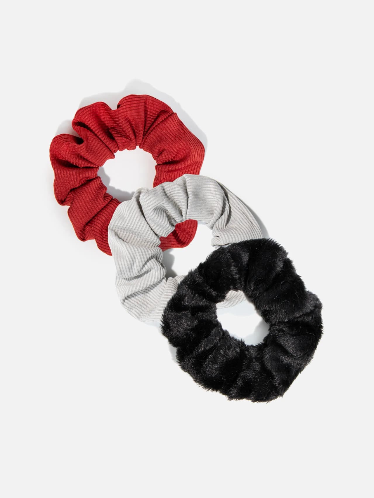 Tre scrunchies i svart, rött och grått, varav en med mjuk fluffig yta