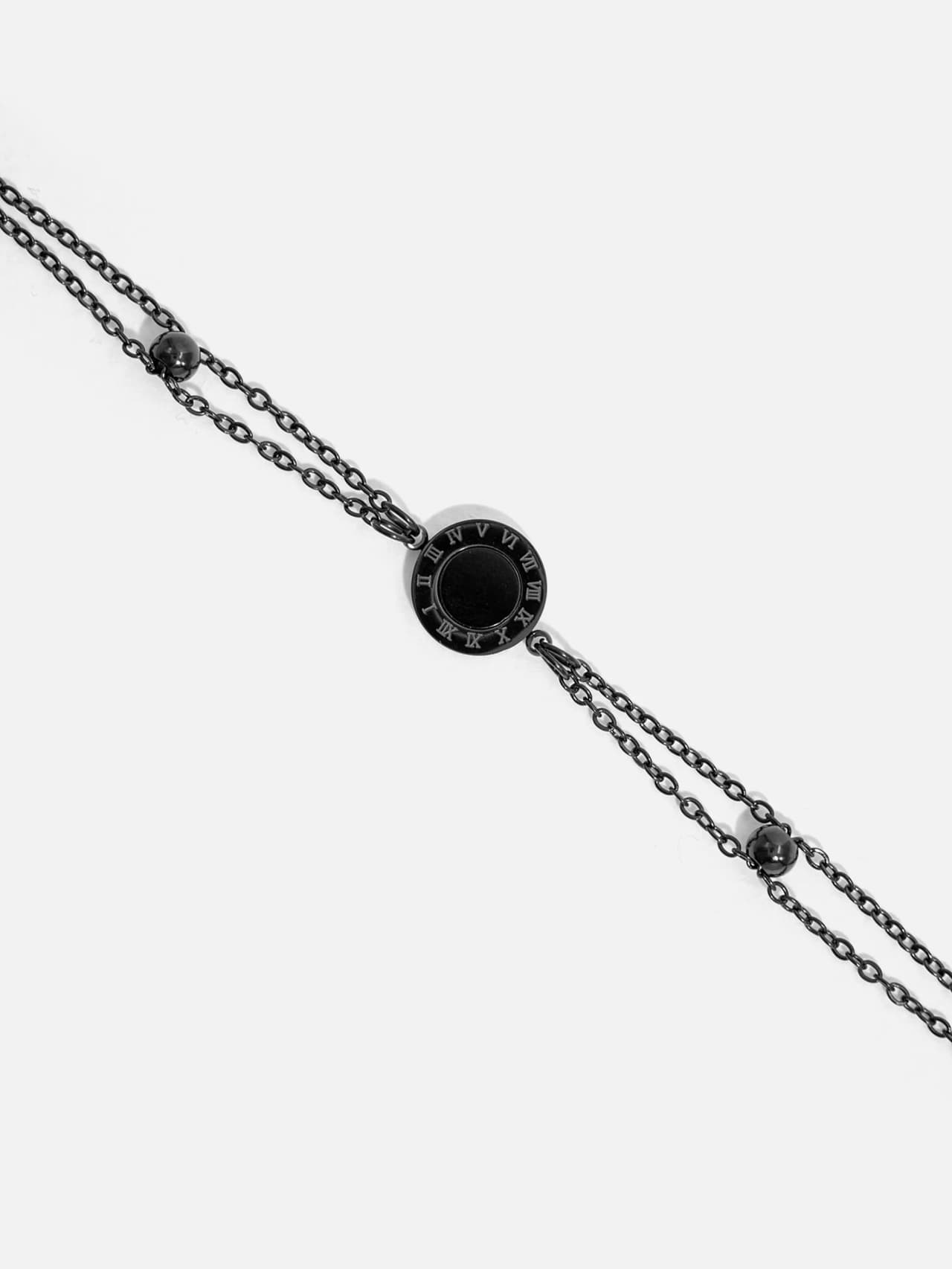 Närbild av svart armband i rostfritt stål med två tunna kedjor och justerbar design