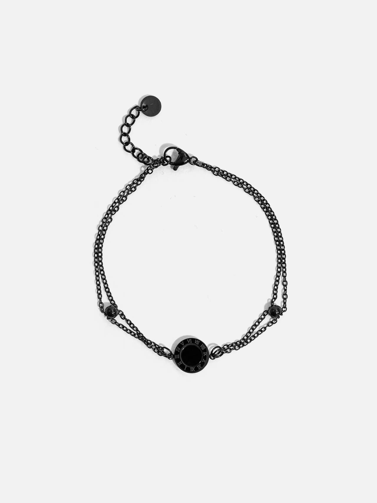 Svart dubbelkedjat armband i rostfritt stål med rund mittdetalj på ljus bakgrund