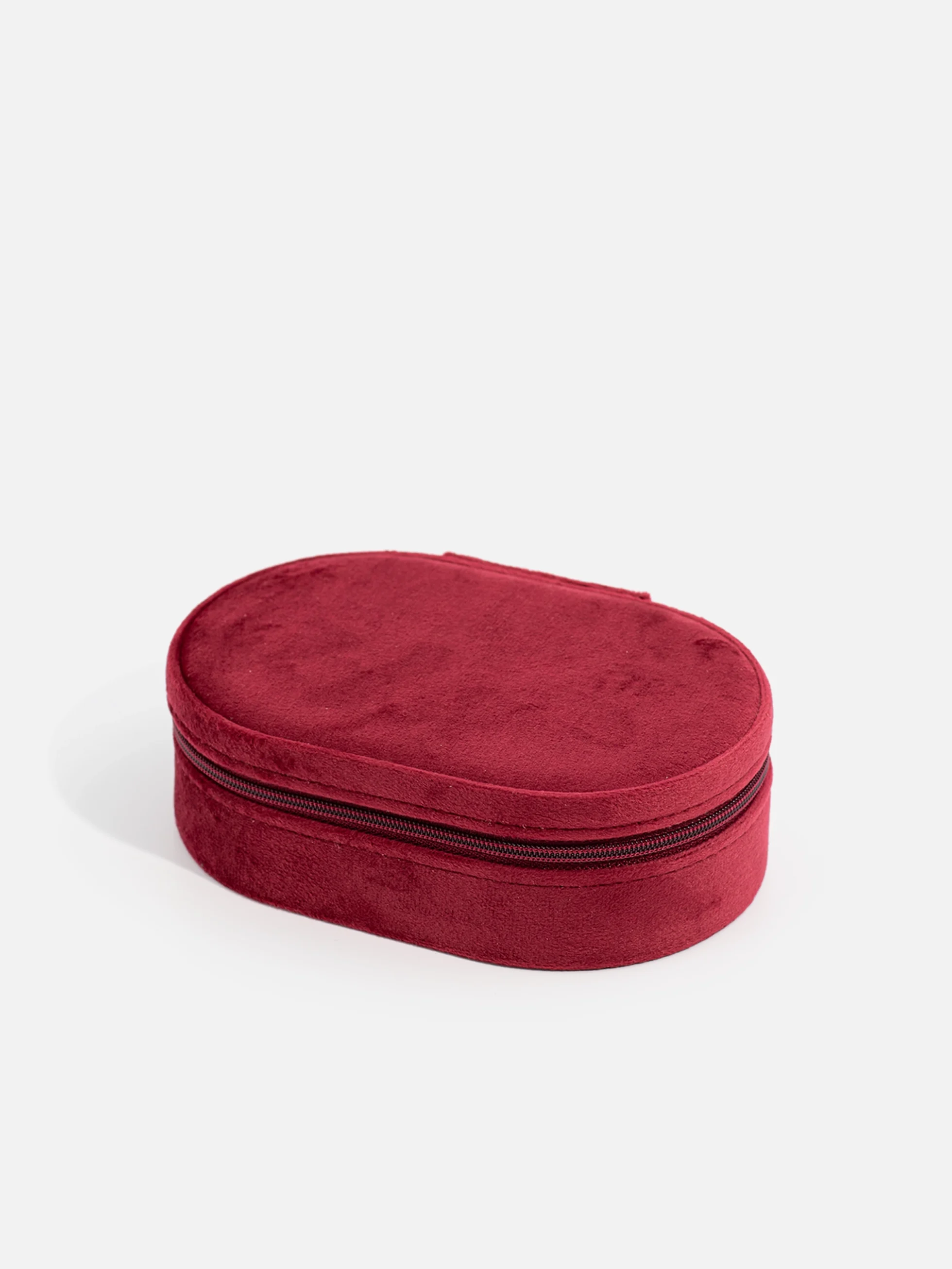 Rött ovalt resesmyckeskrin i sammet med beige insida. Perfekt för säker och elegant förvaring av smycken på resan.